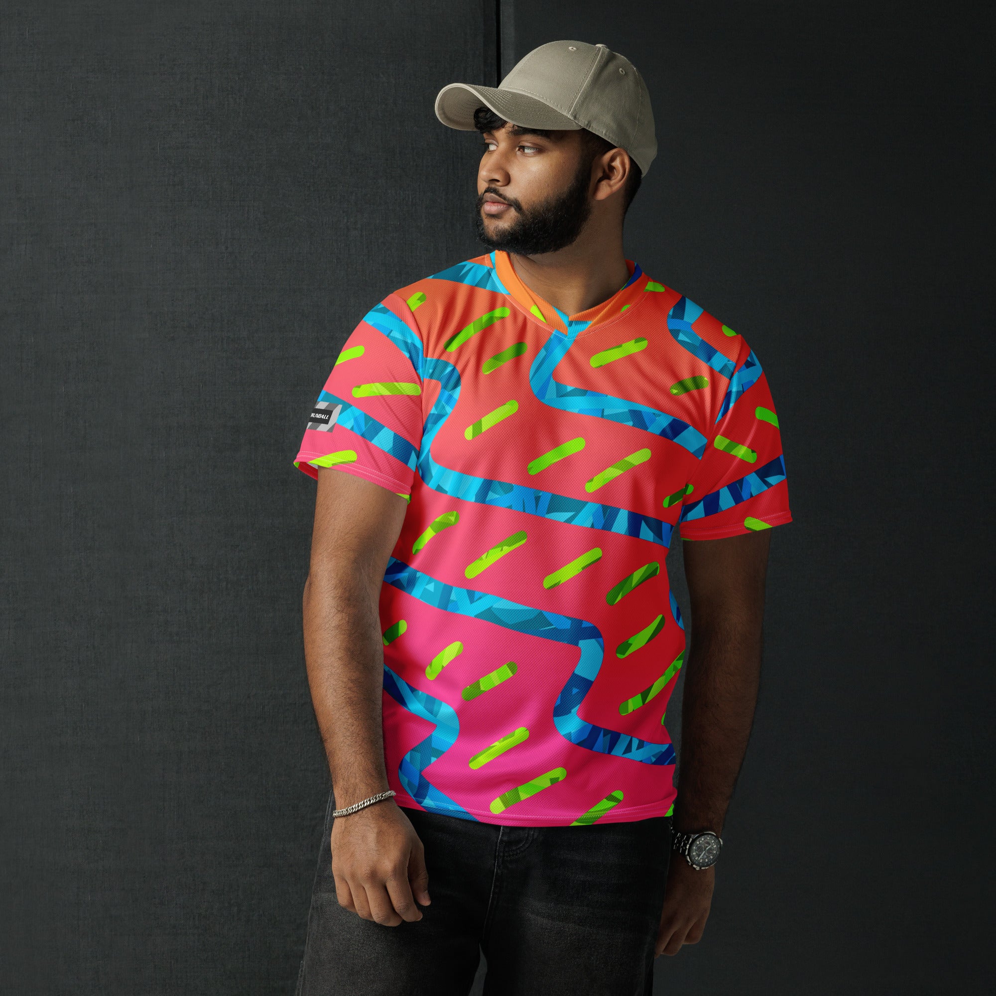 Man wearing a colorful patterned shirt and cap against a black background