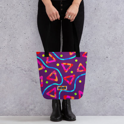 Person holding a colorful tote bag with geometric patterns against a gray background