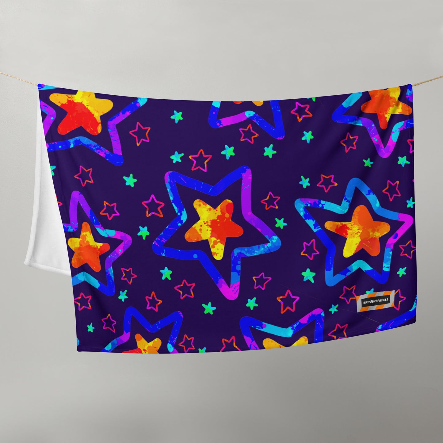Colorful star patterned towel hanging on a line against a gray background