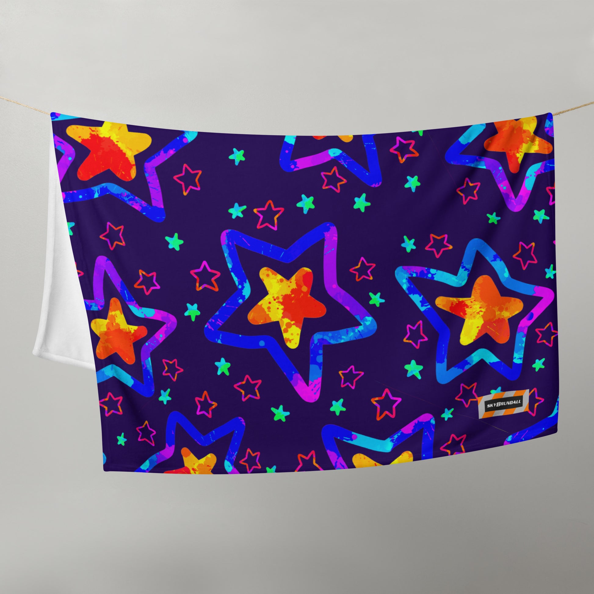 Colorful star patterned towel hanging on a line against a gray background