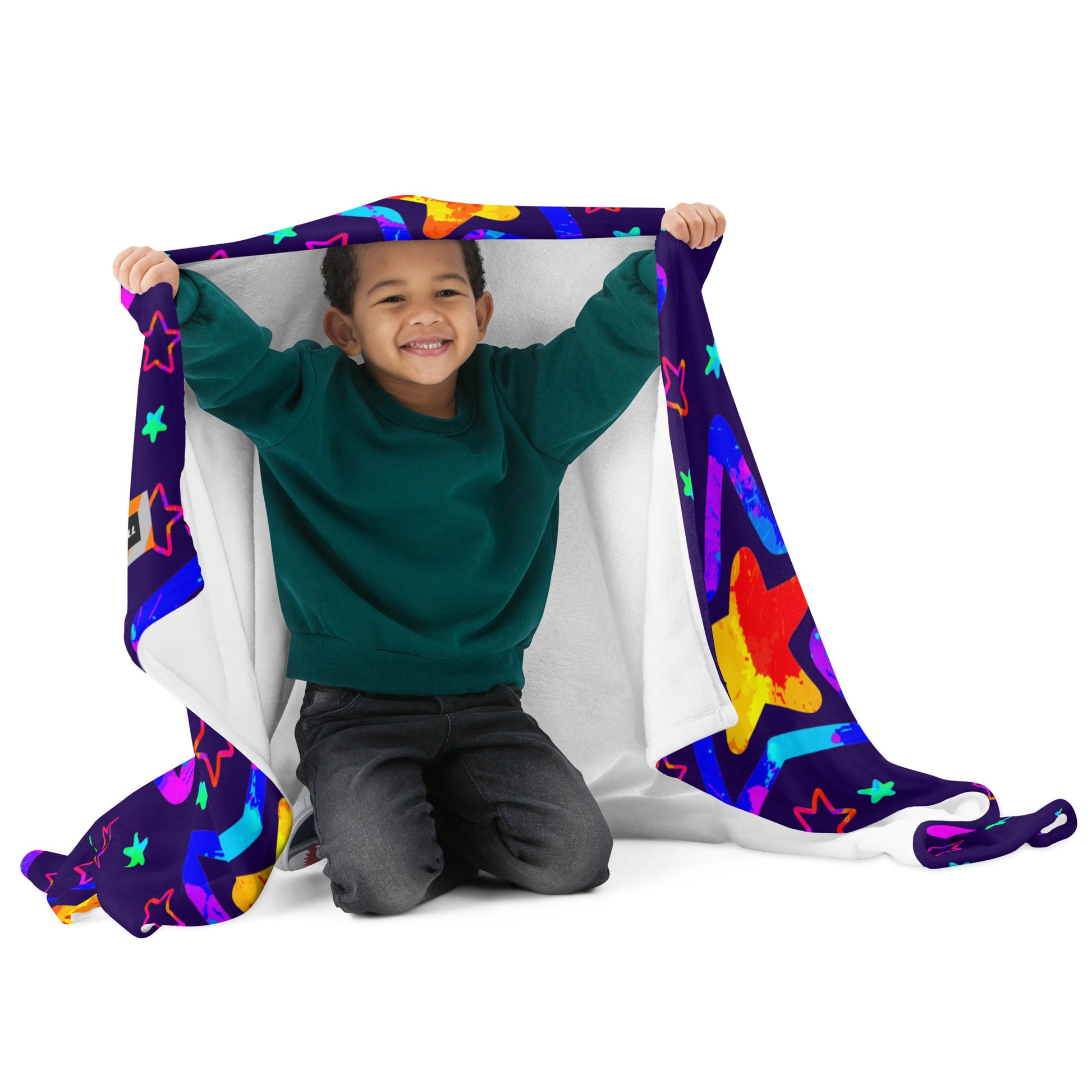Child playing with a colorful star-patterned blanket on a white background