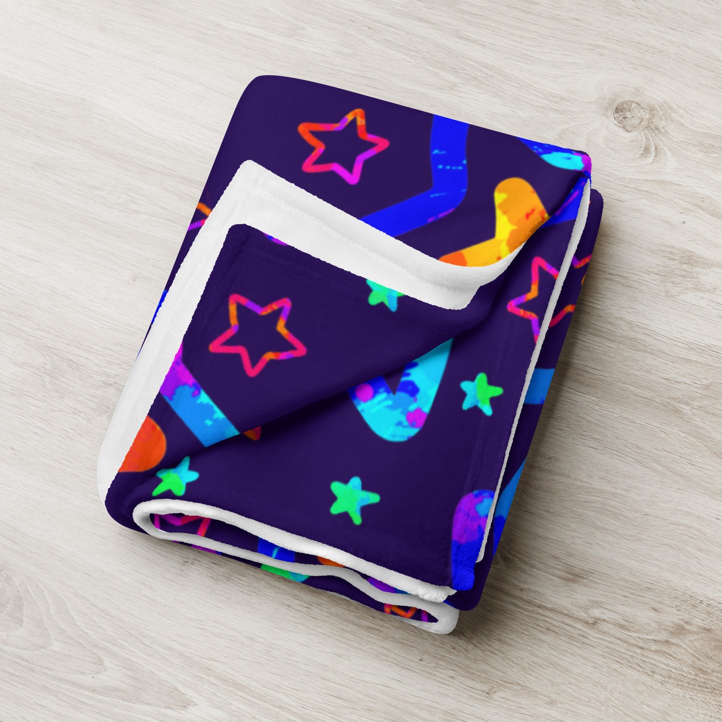 Folded blanket with colorful star pattern on a light wooden surface